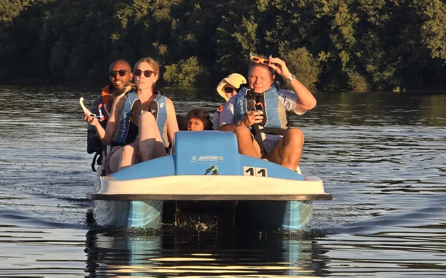 Un groupe d'amis en pédalo sur le lac au coucher du soleil