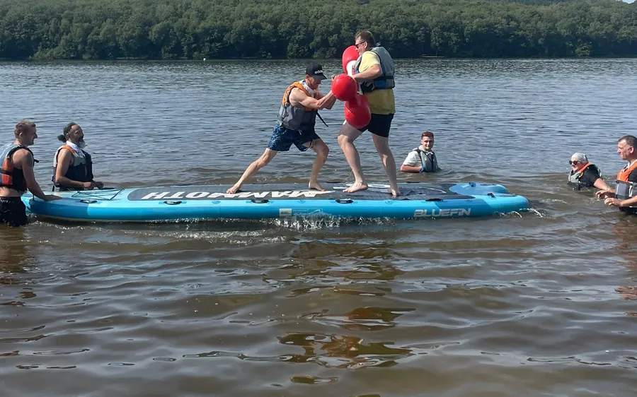 Deux amis s'affrontent sur un paddle géant sous les encouragements de leurs proches