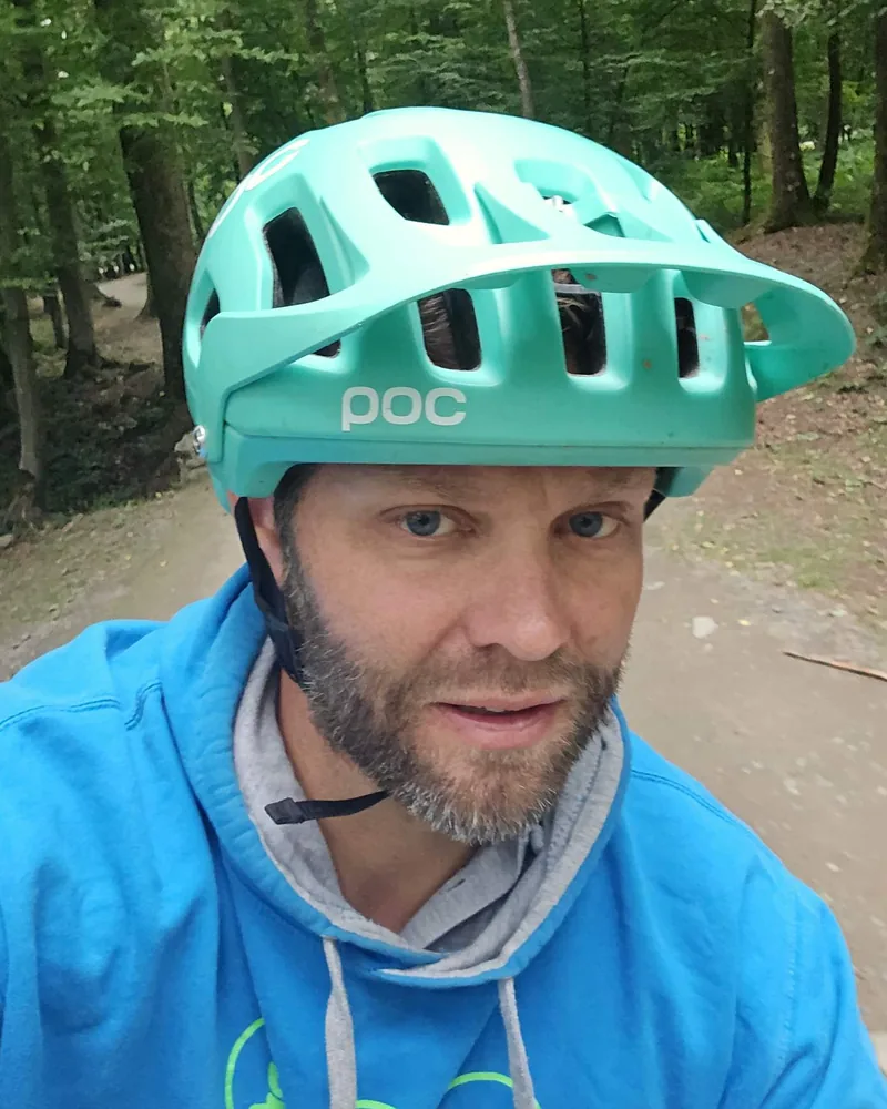 Simon Schwartz op de mountainbike, met helm, in het bos rond het meer